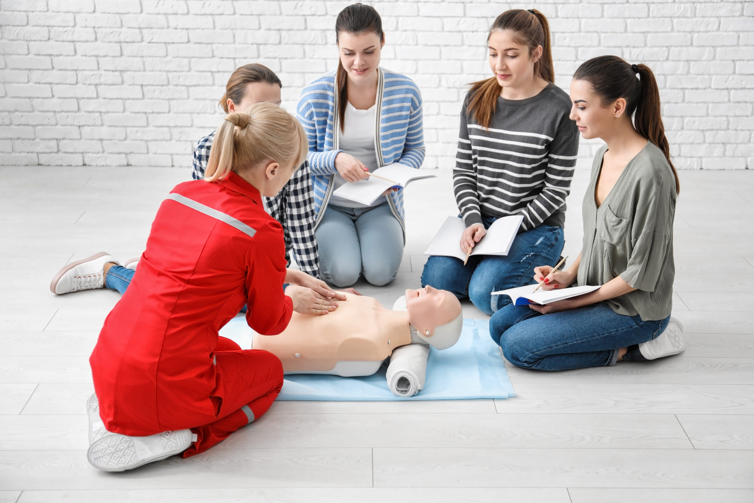 Group of people practicing CPR on mannequin at first aid class